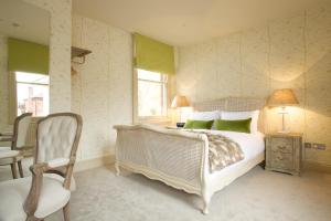 a bedroom with a bed with green pillows and a chair at The Northgate in Bury Saint Edmunds