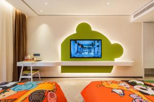 a room with a bed and a tv on a wall at Panda Sleepy Hotel（Chengdu Panda Base) in Chengdu