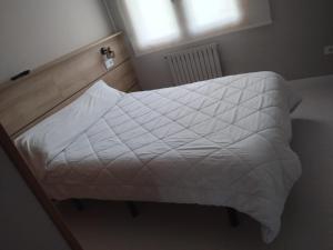 a bed with a white comforter in a bedroom at Ruta Esmeralda in Baamonde