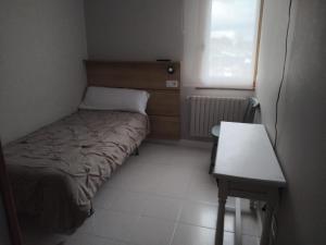 a small bedroom with a bed and a table at Ruta Esmeralda in Baamonde