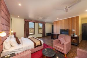 a bedroom with a bed and a chair and a television at La Comfort By shrpl in Gurgaon