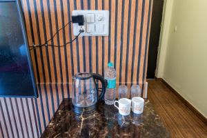 a counter with water bottles and cups on it at La Comfort By shrpl in Gurgaon