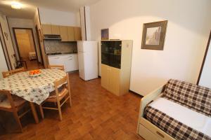 a small room with a kitchen and a table and a bed at Residence Schubert in Lignano Sabbiadoro