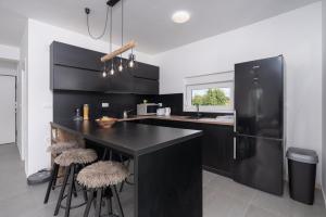 a kitchen with black cabinets and a black refrigerator at Premium Apartment Obatnice with Pool in Povljana