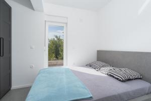 a bed in a white room with a window at Premium Apartment Obatnice with Pool in Povljana