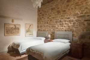 two beds in a bedroom with a stone wall at Wp Relais Mazzini in Montalcino