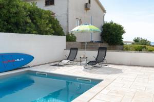 two chairs and an umbrella next to a swimming pool at Premium Apartment Obatnice with Pool in Povljana +42 photos
