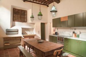 a kitchen with a wooden table and green cabinets at Wp Relais Mazzini in Montalcino