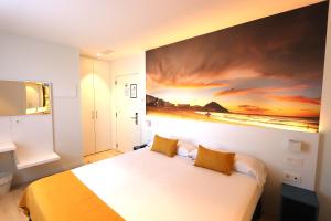 a bedroom with a bed with a painting on the wall at Pension y Apartamentos Txingurri Experience in Astigarraga