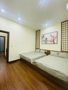two beds in a room with wooden floors at CHIRU House Ninh Bình in Ninh Binh