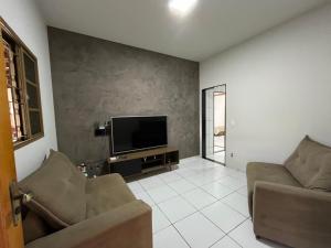 a living room with two couches and a flat screen tv at Casa aconchegante com 2 quartos, próximo ao Centro, UFU, Center Shopping e Convention, Hospitais e Aeroporto in Uberlândia