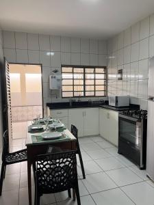 a large kitchen with a table and chairs in it at Casa aconchegante com 2 quartos, próximo ao Centro, UFU, Center Shopping e Convention, Hospitais e Aeroporto in Uberlândia