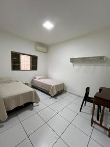 a bedroom with two beds and a table and a desk at Casa aconchegante com 2 quartos, próximo ao Centro, UFU, Center Shopping e Convention, Hospitais e Aeroporto in Uberlândia