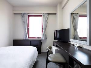 a hotel room with a bed and a desk and a television at KOKO STAY Miyakonojo in Miyakonojō