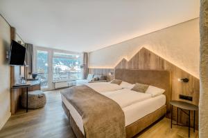 a bedroom with a large bed and a large window at Hotel Kreuz & Post Grindelwald in Grindelwald