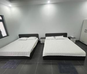 two beds in a room with white walls at Tú Nguyên Motel in Ban Beng