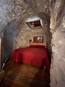 a bedroom with a red bed in a stone wall at La Torre della Bella Ragazza in Suvereto
