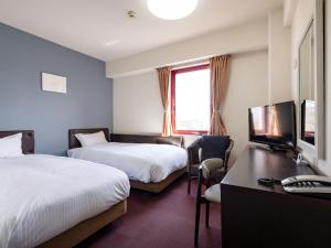 a hotel room with two beds and a desk and a television at KOKO STAY Miyakonojo in Miyakonojō +56 photos