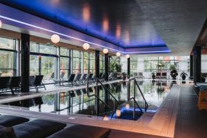 a swimming pool with chairs in a building at Linsberg Asia Hotel, Spa & Therme - Adults Only in Bad Erlach