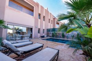 a patio with chairs and a pool in a house at Villa Palms de l'Atlas in Marrakesh