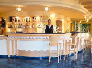 a man standing behind a bar in a restaurant at Hotel Ipomea Club in Capo Vaticano +57 photos