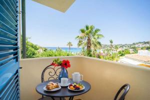 a table with a breakfast on a balcony with a view of the ocean at Hotel Ipomea Club in Capo Vaticano