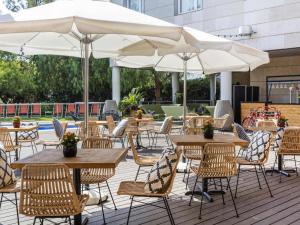 an outdoor patio with tables and chairs and umbrellas at Novotel Barcelona Cornellà in Cornellà de Llobregat