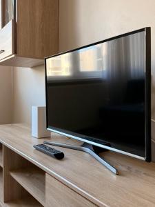 a flat screen tv sitting on a table with a remote control at Apartamentai Jonavoje #1 in Jonava