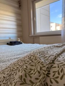 a bedroom with a bed with a blanket with a window at Apartamentai Jonavoje #1 in Jonava