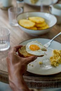a person holding a plate of food with an egg on it at ISOLA - Surf House in Ahangama