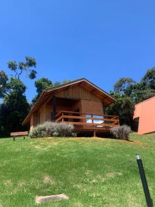 a large wooden building with a bench in the grass at chalés Roma in Santo Antônio do Pinhal