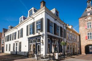 a white building with black shutters on a street at The Carriage House - Historic 3-Bedroom Apartment near Utrecht - Huize de Lekpoort Vianen in Vianen