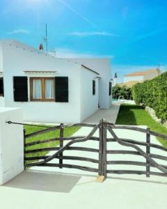 a white house with a fence in front of it at Villa Mar in Cala en Bosc