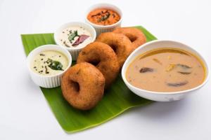 a plate of food with soup and onion rings and dip at hotel monville akota in Vadodara