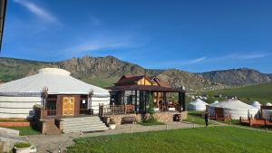 a building with a yurt with mountains in the background at Bayalag Resort in Yoliin Hural