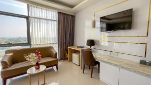 a hotel room with a couch and a desk and a tv at Elegant Airport Hotel in Bangkok