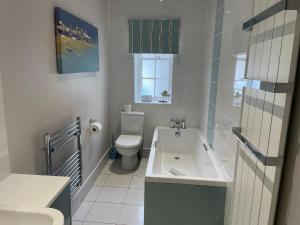 a bathroom with a toilet and a sink and a tub at Safe Harbour in Weymouth +30 photos