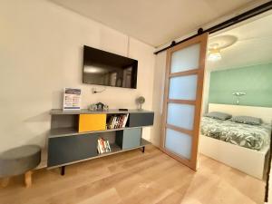 a room with a bed and a shelf with a television at Central Océan in Les Sables-d'Olonne