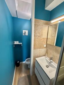 a blue bathroom with a sink and a toilet at Central Océan in Les Sables-d'Olonne
