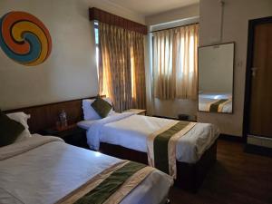 a hotel room with two beds and a mirror at Boudha Orange Hotel in Kathmandu