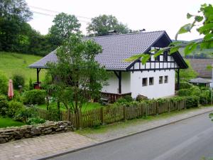 una casa blanca con techo negro y valla en Ferienwohnung Schmallenberg, en Schmallenberg