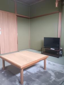 a wooden table in a room with a flat screen tv at 波松の家 in Awara +4 photos