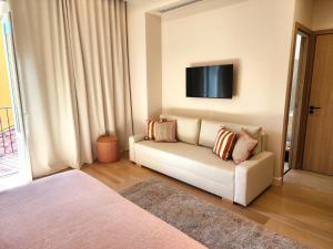 a living room with a couch and a tv on the wall at La Bastide Du Port - Hôtel de Charme in Saint-Tropez