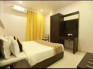 a bedroom with a bed and a desk and a television at Hotel Anchal Villa By YB Hotel in Udaipur