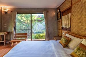 a bedroom with a large bed and a large window at Lion Cafe Resort in Ban Huai Sieo