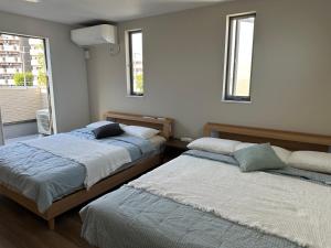 two beds in a room with two windows at yuanquanHOTEL in Osaka