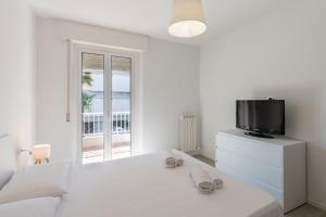 a white bedroom with a tv and a bed at Les Fleurs Pool Residence in Bordighera +19 photos