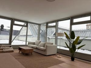 a living room with a couch and a table and windows at Luga Homes - Augustusplatz in Leipzig