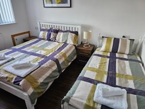 a bedroom with two beds and a table with a lamp at Spacious 3-Bedroom House Near Leeds City Centre By Homebird Property Management Short Lets & Serviced Accommodation Leeds With En-Suite Bathrooms & Free Parking in Leeds