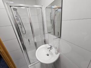 a white bathroom with a sink and a shower at Spacious 3-Bedroom House Near Leeds City Centre By Homebird Property Management Short Lets & Serviced Accommodation Leeds With En-Suite Bathrooms & Free Parking in Leeds